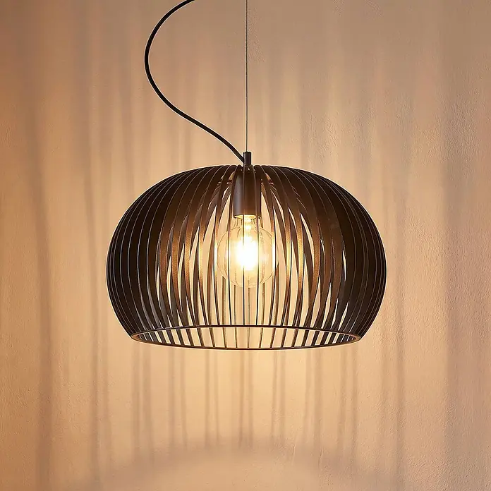 Lindby Pendelleuchte Jusra - schwarz, Schwarz, E27 - Dunkle Hängeleuchte mit Lamellenschirm und glühender Edison-Birne, wirft Schatten an eine helle Wand.