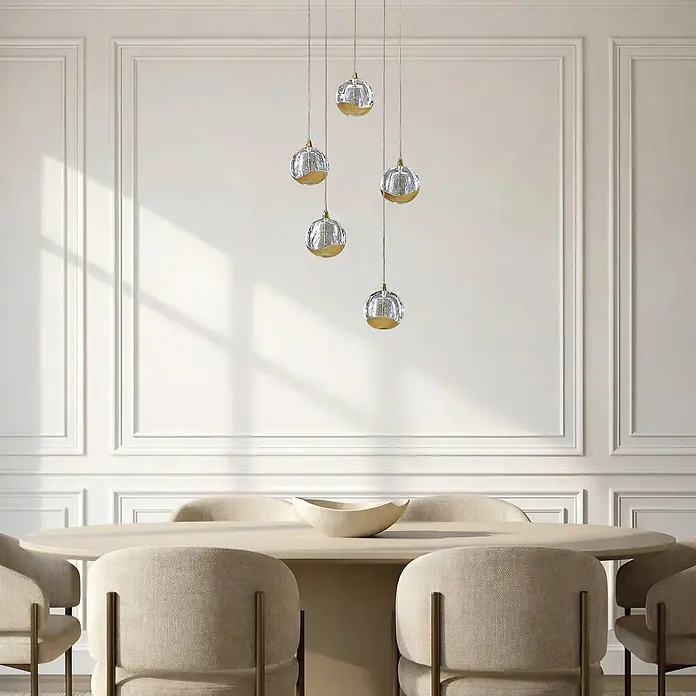 Lucande Pendelleuchte Hayley - L x B x H: 30 x 30 x 150 cm, klar / transparent, klar, gold - Fünf Glas-Pendelleuchten mit Goldakzenten hängen in verschiedenen Längen über einem beigefarbenen Esstisch.