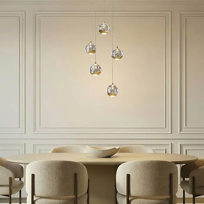 Lucande Pendelleuchte Hayley - L x B x H: 30 x 30 x 150 cm, klar / transparent, klar, gold - Gruppe von fünf kugelförmigen Pendelleuchten mit strukturiertem Glas und goldfarbenen Sockeln, die einen modernen Esstisch beleuchten.