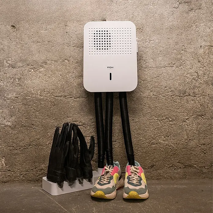 WDH Schuhtrockner - Schuhwärmer - Weißer wandmontierter Schuh- und Handschuhtrockner mit schwarzen Schläuchen, trocknet bunte Sneaker und schwarze Handschuhe.