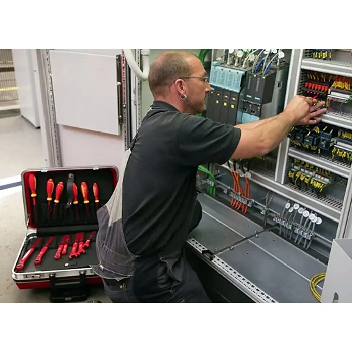 Stahlwille Werkzeugkoffer 13300 VDE 48-teilig - 48 -tlg. - Elektriker arbeitet an einer Schalttafel mit isolierten Werkzeugen aus einem roten Werkzeugkoffer.