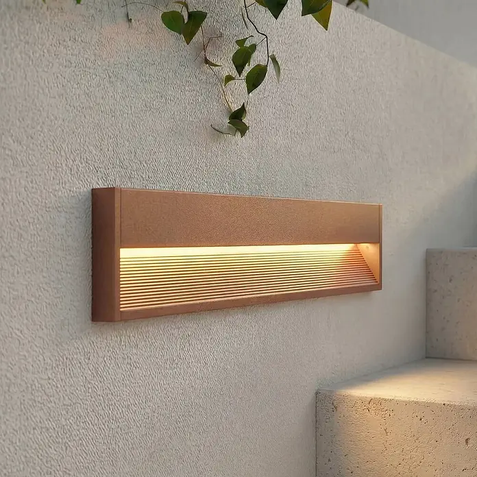 Lucande Außenwandleuchte Trevin - 60 x 60 x 12,8 cm, braun / rost, IP65 - Braune rechteckige Wandleuchte mit warmem Licht an einer strukturierten Wand, beleuchtet Stufen.