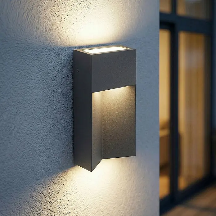 Lucande Außenwandleuchte Kaholo - schwarz, schwarz, IP44 - Anthrazitfarbene Außenwandleuchte mit warmer Up- und Downlight-Beleuchtung, an strukturierter Wand montiert.