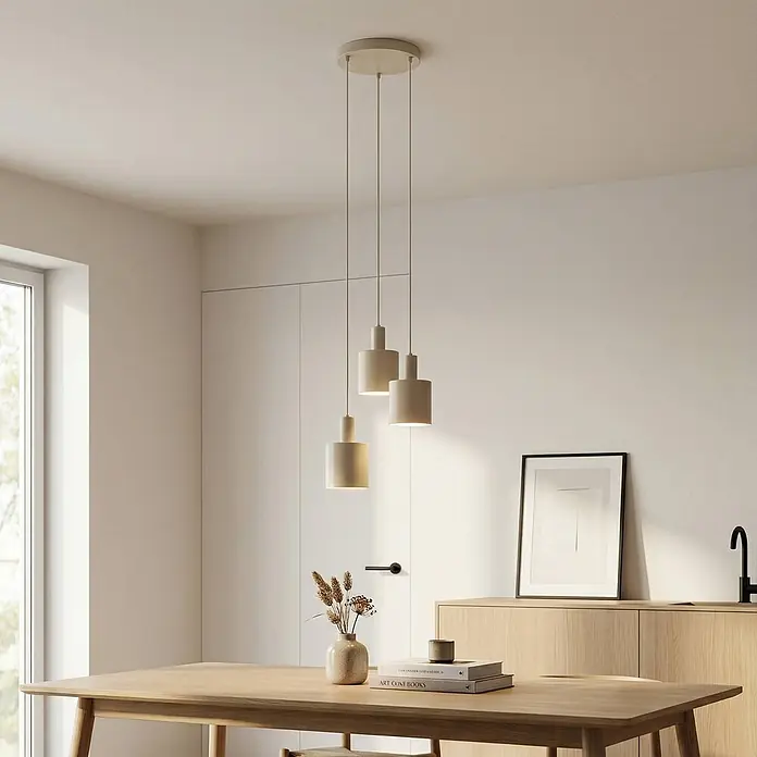Lindby Pendelleuchte Ovelia - L x B x H: 43 x 43 x 150 cm, creme / amber, beige, E27 - Drei matte, hellfarbene Pendelleuchten hängen in verschiedenen Höhen über einem Holztisch und beleuchten den Raum mit sanftem Licht.