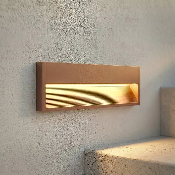 Lucande Außenwandleuchte Trevin - 40 x 40 x 12,8 cm, braun / rost, IP65 - Rechteckige bronzefarbene Außenstufenleuchte, die eine strukturierte Wand und Betontreppen beleuchtet.