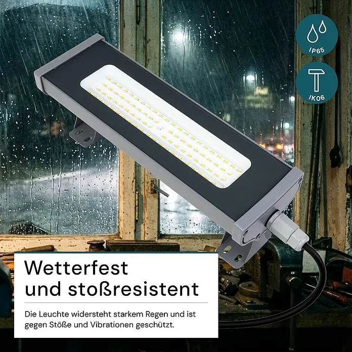 Luxula LED-Strahler LED-Hallenstrahler - 50 W, 6.200 lm, 5.000 K, L x B x H: 332 x 95 x 53 mm, IP65 - Rechteckige schwarze und graue LED-Leuchte, im Freien vor einem regnerischen Fenster montiert, betont ihre wetterfeste und stoßfeste Bauweise.