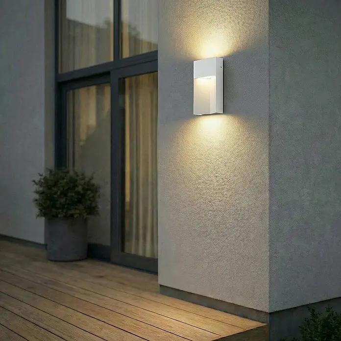 Lucande Außenwandleuchte Kaholo - alu / grau / zink, alu / grau / zink, IP44 - Weiße rechteckige Außenwandleuchte an einer Außenwand montiert, wirft warmes Licht nach oben und unten auf Wand und Holzterrasse.