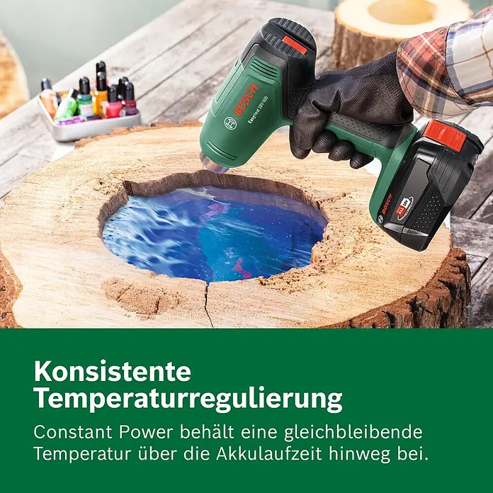 Bosch Power for All 18V Akku-Heißluftgebläse EasyHeat 18V-500 - 18 V, Ohne Akku, Temperaturbereich: 350 °C - 450 °C - Grüne und schwarze Bosch EasyHeat 18V-500 Akku-Heißluftpistole, von einer behandschuhten Hand gehalten, erwärmt blaues Harz in einer Holzplatte.