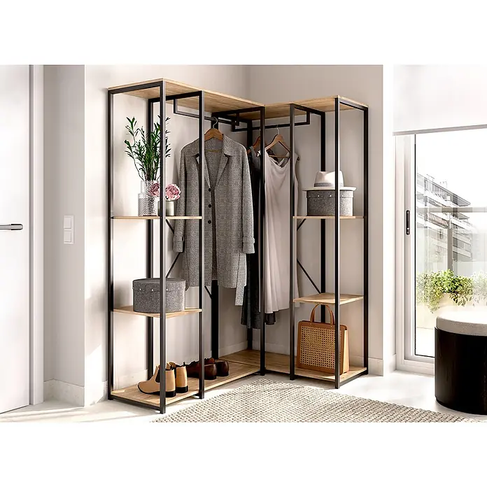 Dekit Armario para ropa Trok - L x An x Al: 130,4 x 90 x 167 cm, Negro/Roble, Acero/Melamina - Armario de esquina con marco de metal negro y estantes de madera clara, con ropa, zapatos y decoración en una habitación.