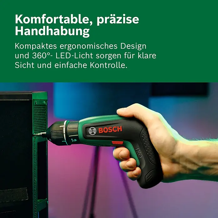 Bosch Akkuschrauber IXO 8 - 4 V, 1 Akku, 2 Ah, 6,5 Nm, 14 -tlg. - Eine Hand hält einen grün-schwarzen Bosch Akku-Schrauber und schraubt in eine schwarze Platte. Ergonomisches Design bietet präzise Handhabung mit 360° LED-Licht.