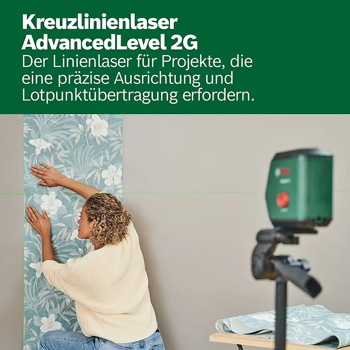 Bosch Kreuzlinienlaser Advanced Level 2G Set - Max. Arbeitsbereich: 15 m - Kreuzlinienlaser AdvancedLevel 2G projiziert eine grüne Linie, die einer Frau beim Ausrichten von Tapeten hilft.