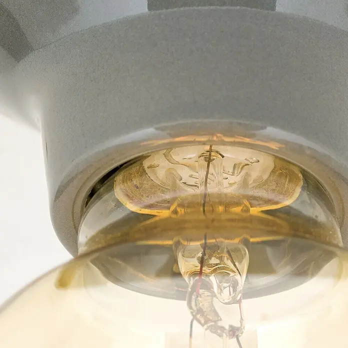 Orion Leuchten Deckenleuchte rund - E27 - Nahaufnahme einer bernsteinfarbenen Edison-Glühbirne in einer hellgrauen, strukturierten Keramikfassung mit sichtbaren Glühfäden.