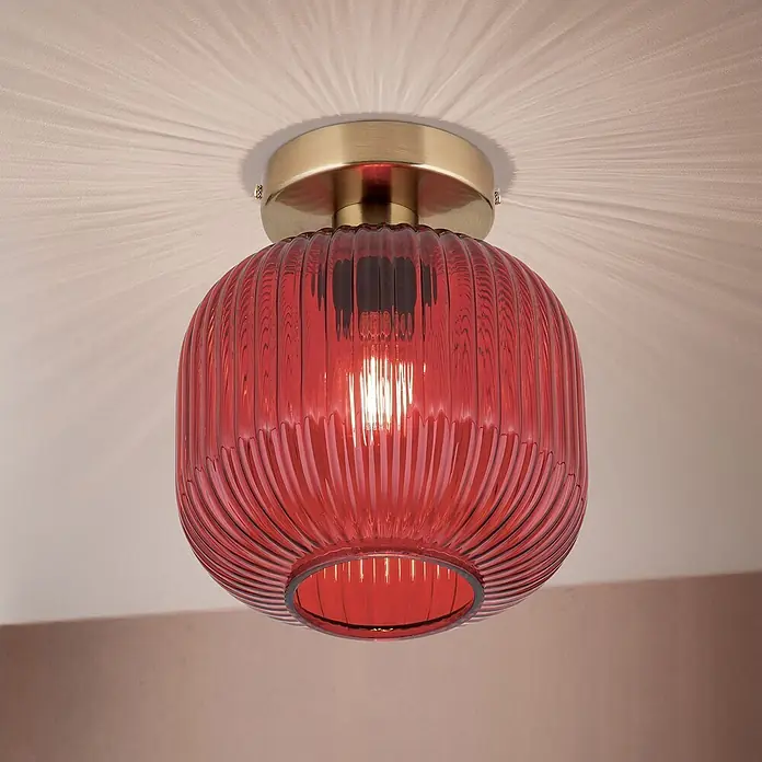 Orion Leuchten Deckenleuchte rund - E27 - Deckenleuchte mit rotem geripptem Glasschirm und Messingfassung, die ein radiales Lichtmuster an die Decke wirft.