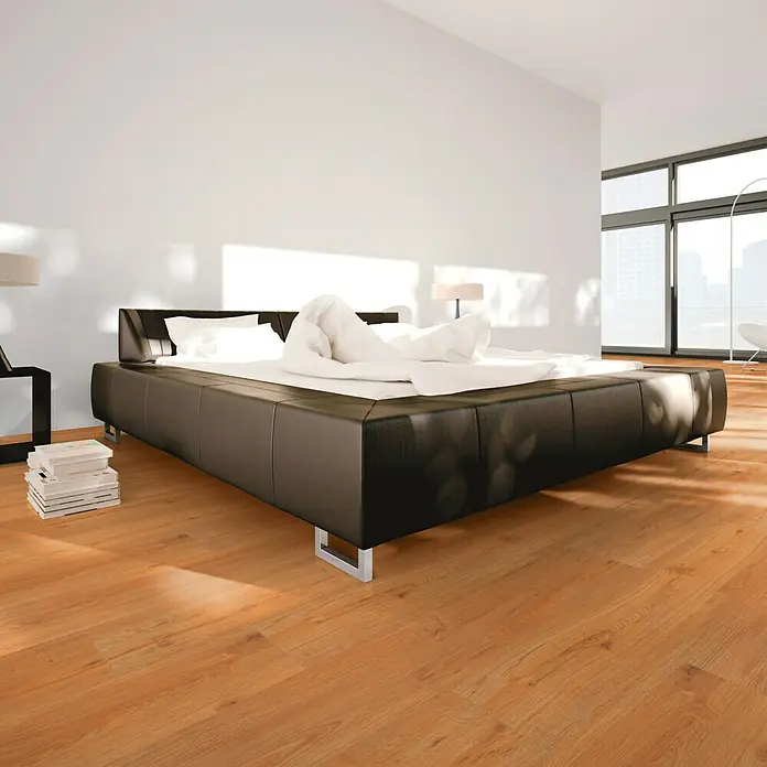 b!design Vinylbodenmuster Clic Eiche Natural - 190 x 200 x 3 mm, Landhausdiele - Ein modernes Schlafzimmer mit einem großen, schwarzen Lederbett, das im Mittelpunkt des Raumes steht. Helle Holzböden und viel Tageslicht.
