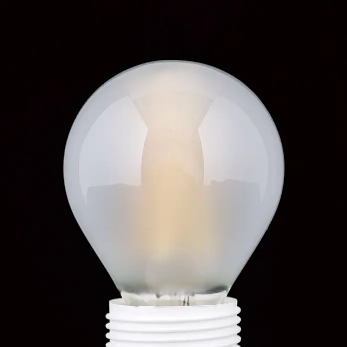 Orion Leuchten LED-Lampe - E27, Dimmbar, Warmweiß, 720 lm, 6 W - Beleuchtete, mattweiße Glühbirne mit weißem Schraubsockel, warm leuchtend vor schwarzem Hintergrund.