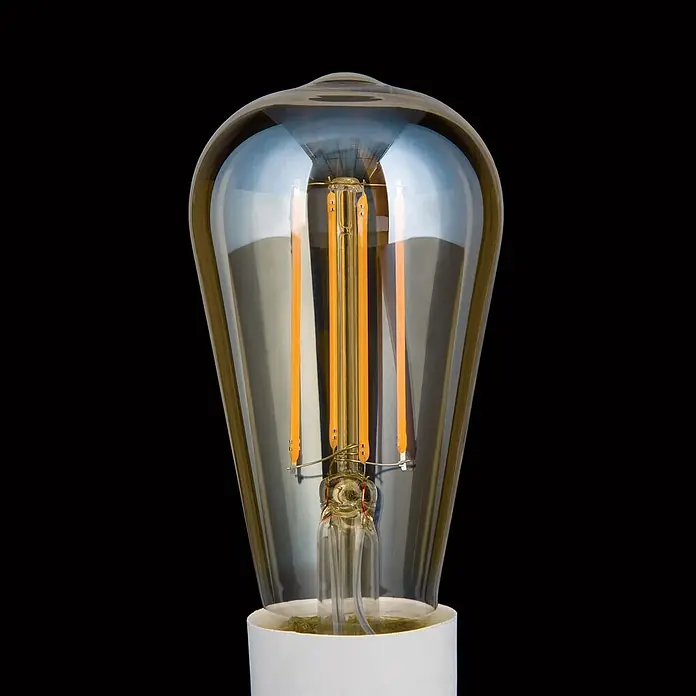 Orion Leuchten LED-Lampe - E27, Dimmbar, Warmweiß, 550 lm, 6 W - Vintage-LED-Glühbirne mit klarem, länglichem Glaskörper und sichtbaren, warmen bernsteinfarbenen Filamenten auf weißem Sockel.