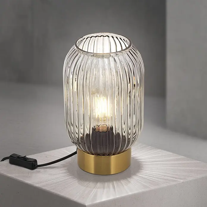 Orion Leuchten Tischleuchte - 40 W, L x B x H: 14 x 14 x 24 cm, E27 - Eine beleuchtete Tischlampe mit geripptem Klarglasschirm und poliertem Messingsockel, die Lichtmuster wirft.