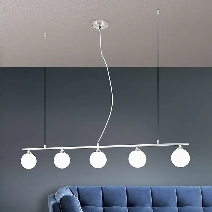 Orion Leuchten Pendelleuchte - L x B x H: 120 x 12 x 150 cm, G9 - Fünfflammige Pendelleuchte mit weißen Kugelgläsern und gebürstetem Chrombalken, über einem blauen Sofa hängend.