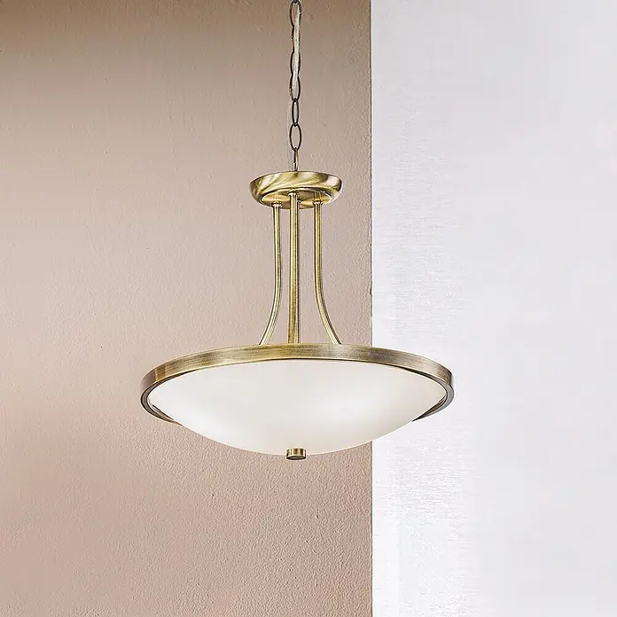 Orion Leuchten Pendelleuchte rund - E27 - Kronleuchter aus Messing mit weißem, mattiertem Glasdiffusor, hängt in einer Raumecke.