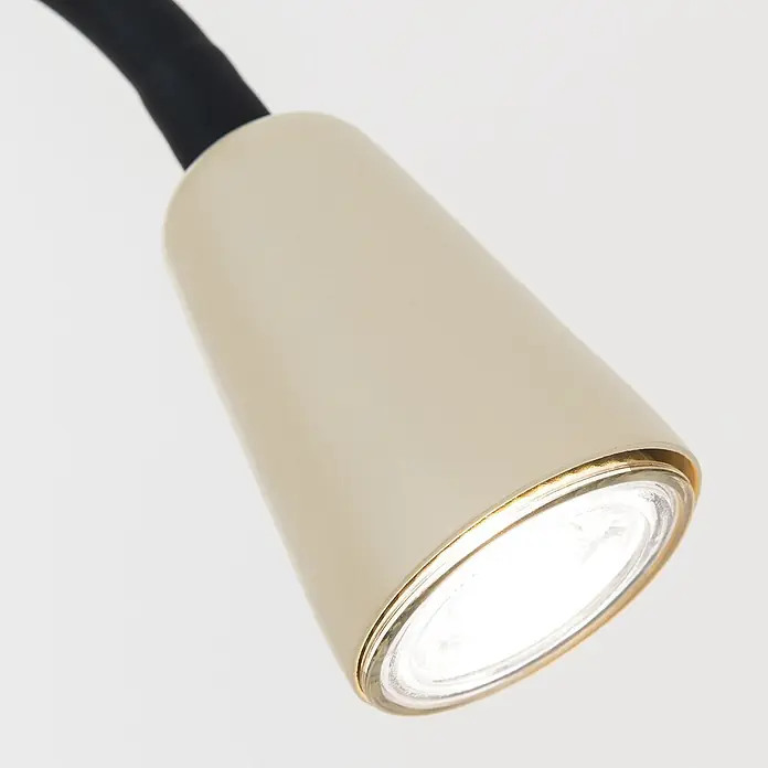Orion Leuchten Klemmleuchte - 40 W, L x B x H: 7,5 x 24 x 58 cm - Nahaufnahme eines beigen konischen Lampenkopfes mit Goldrand und hellem Licht, an einem schwarzen Flexarm.