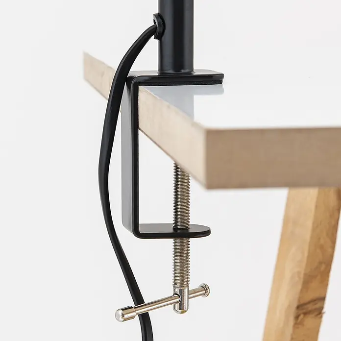 Orion Leuchten Klemmleuchte - 40 W, L x B x H: 7,5 x 24 x 58 cm - Schwarze Metall-Tischklemme mit silbernem Schraubmechanismus, die ein schwarzes Kabel an einer weißen Tischplatte mit Holzkante befestigt.