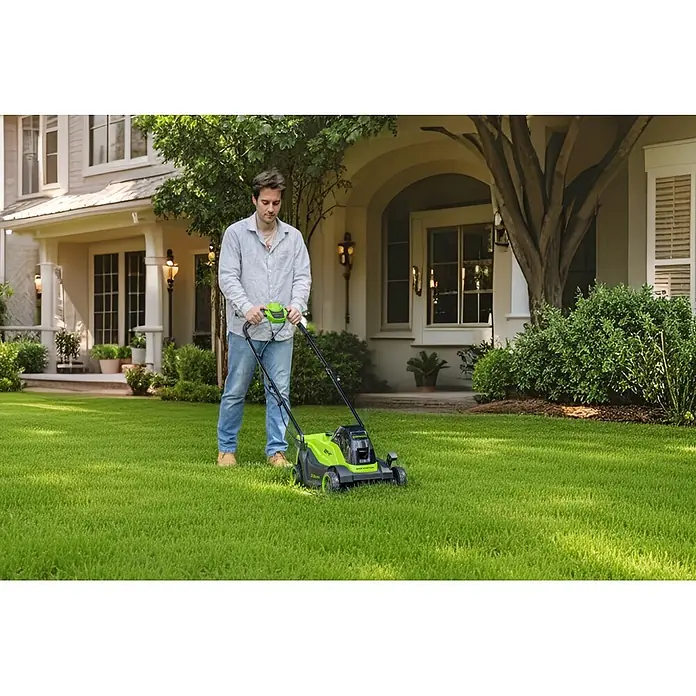 Greenworks Akku-Rasenmäher Gen2 GW 24V BL 4 AH 33 cm - 24 V, 1 Akku, 4 Ah, Schnittbreite: 33 mm - Grüner und schwarzer Elektrorasenmäher, von einem Mann auf einem Rasen verwendet.