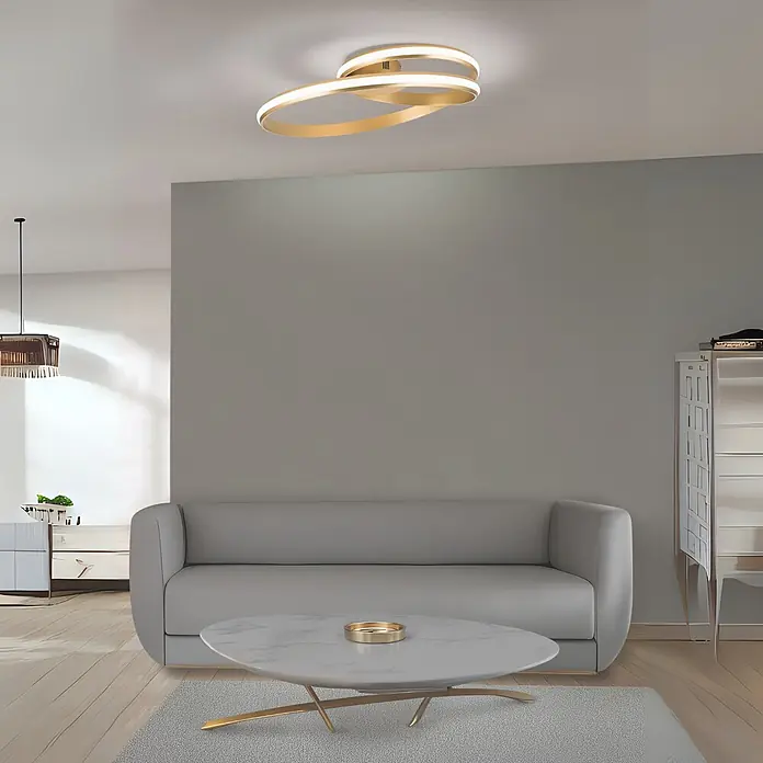Orion Leuchten Deckenleuchte Circus Gold 3000 K -  - Moderne goldene LED-Deckenleuchte mit verschlungenen Ringen, die ein Wohnzimmer beleuchtet.