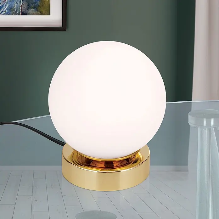 Orion Leuchten LED-Tischleuchte - 3 W, L x B x H: 12,6 x 12,6 x 14 cm, Warmweiß - Kugelförmige Tischlampe aus weißem Glas mit goldenem Fuß und schwarzem Kabel auf Glastisch.