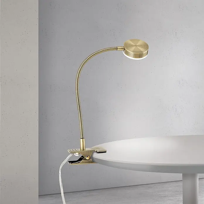 Orion Leuchten LED-Klemmleuchte - L x B x H: 5,5 x 5,5 x 42 cm, 3 W, Lichtfarbe: Kaltweiß - Messingfarbene LED-Klemmleuchte mit flexiblem Schwanenhals, beleuchtet eine weiße Tischfläche.
