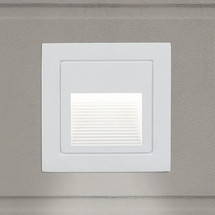 Orion Leuchten LED-Einbauleuchte - L x B x H: 7,2 x 8,5 x 8,5 cm - Weißes quadratisches Einbau-Treppenlicht mit horizontalen Lamellen, das ein sanftes Licht abstrahlt, an einer strukturierten grauen Wand montiert.