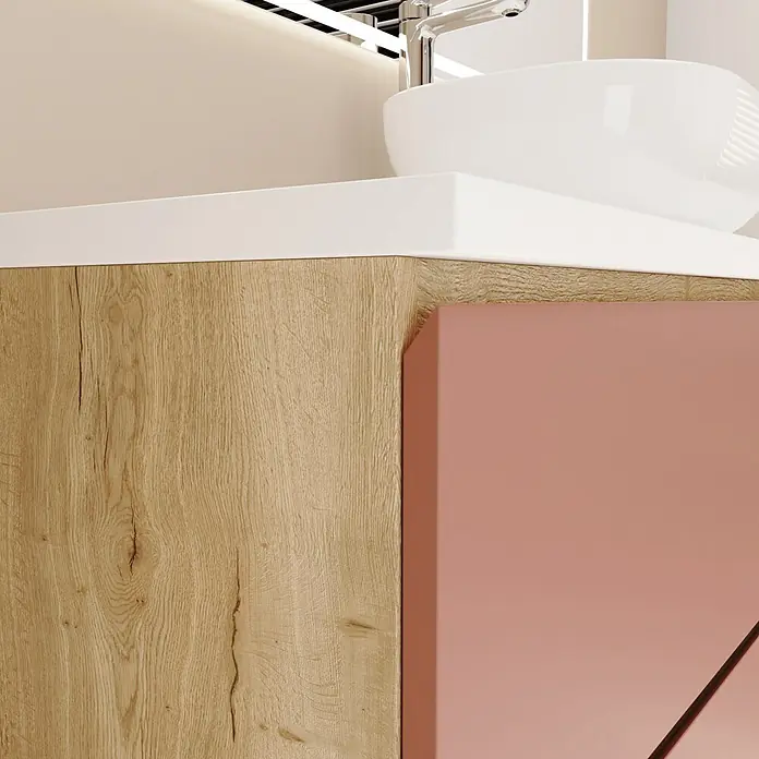Mueble bajo de lavabo Isa - An x Pr x Al: 60 x 44,6 x 54,5 cm, Rose, Apertura con uñero ingletado 45 grados - Primer plano de tocador de baño: lateral de madera clara, frente oro rosa, encimera blanca, lavabo, grifo cromado.