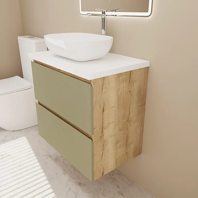 Mueble bajo de lavabo Isa - An x Pr x Al: 60 x 44,6 x 54,5 cm, Verde, Apertura con uñero ingletado 45 grados - Mueble de baño moderno con textura de madera, cajones verde salvia, encimera blanca y lavabo sobre encimera blanco. Inodoro cerca.
