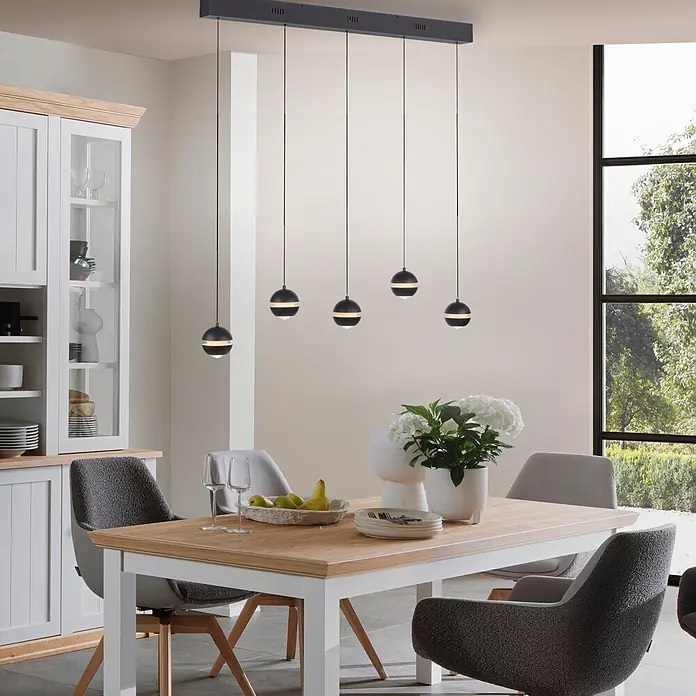 Just Light LED-Pendelleuchte Lini - 4,5 W, L x B x H: 10 x 110 x 22 cm, Schwarz, Warmweiß - Schwarze, rechteckige Pendelleuchte mit fünf kugelförmigen Schirmen, beleuchtet einen hellen Holzesstisch und moderne Stühle im Esszimmer.