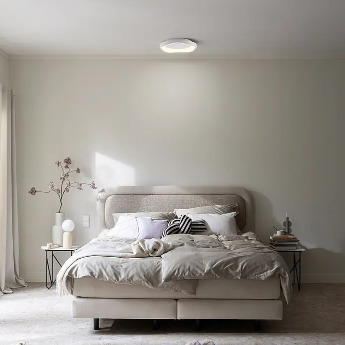Just Light LED-Deckenleuchte rund Monta - 21 W, Ø x H: 40 x 7,5 cm, Weiß, Warmweiß - Weiße, moderne LED-Deckenleuchte mit geschwungenem Design, die ein Schlafzimmer beleuchtet.
