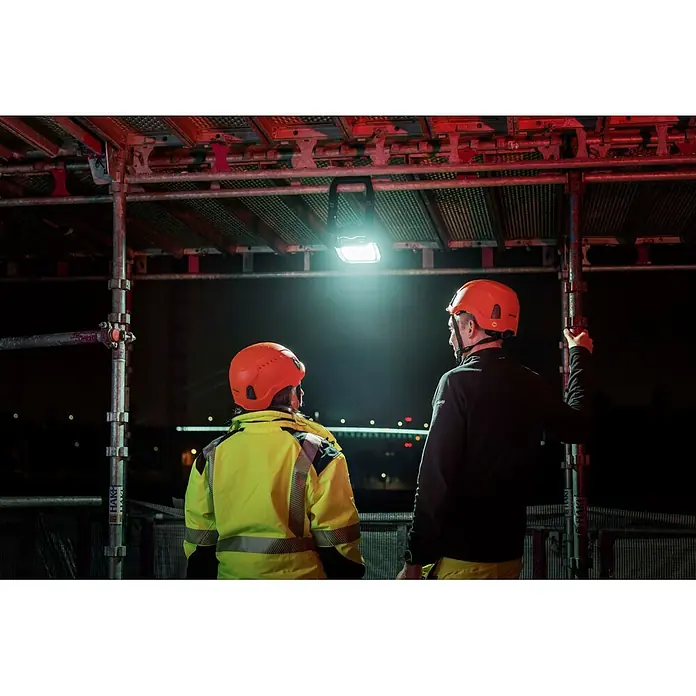 Mareld LED-Strahler Shiny 5000 - 50 W, 5.000 lm, 6.500 K, L x B x H: 28,6 x 18 x 10,2 cm, IP65 - Helle Arbeitsleuchte beleuchtet zwei Arbeiter in Helmen unter Gerüst bei Nacht für bessere Sicht.