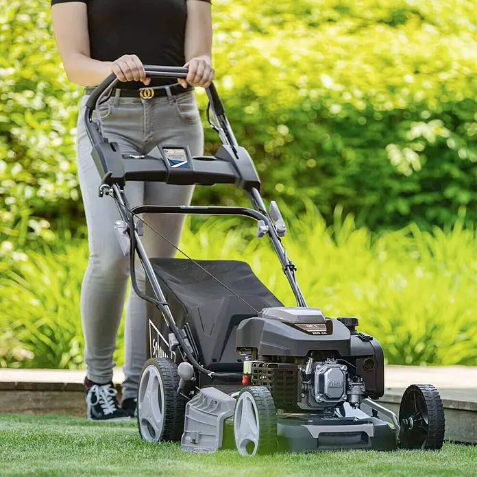Scheppach Benzin-Rasenmäher PML530-225E - 4,4 kW, 224 cm³, Schnittbreite: 53 cm - Eine Person schiebt einen schwarz-grauen Benzin-Rasenmäher.