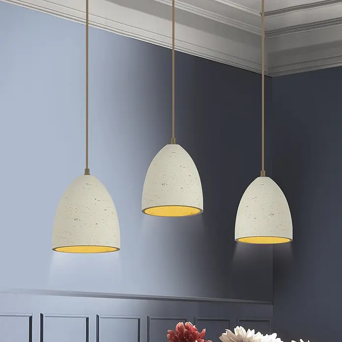 Just Light Pendelleuchte Traventa - L x B x H: 115 x 21 x 120 cm, Travertinoptik, E27, Anzahl Leuchtmittel: 3 Stk. - Drei texturierte beigefarbene Pendelleuchten mit goldener Innenseite hängen vor einer blauen Wand und spenden warmes Licht.