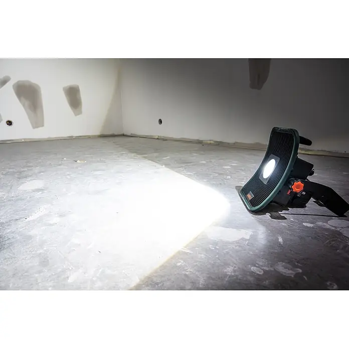 Mareld LED-Strahler Blaze 6500 - 50 W, 6.500 lm, 5.500 K, L x B x H: 14 x 27,2 x 30 cm, IP40 - Grüne und schwarze Arbeitsleuchte, die einen Betonboden und unfertige Wände in einem Rohbau beleuchtet.