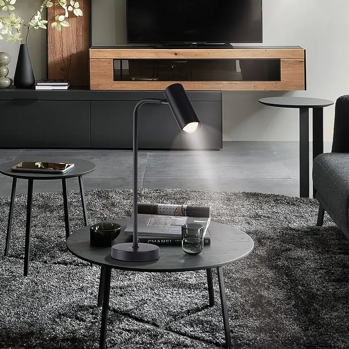 Just Light Akku-Tischleuchte Rik - L x B x H: 28 x 13 x 46 cm, Warmweiß, 2 W, IP20 - Schwarze Tischleuchte mit gebogenem Arm und zylindrischem Kopf, beleuchtet einen Couchtisch im modernen Wohnzimmer.