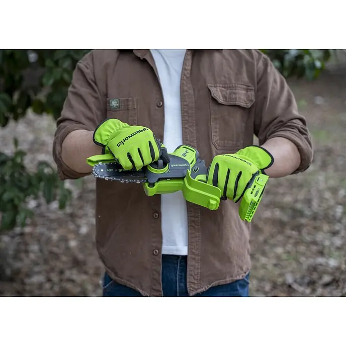 Greenworks Einhand-Akku-Kettensäge Mini GW 24V BL 10 cm - 24 V, 2 Ah, Li-Ionen, 1 Akku, Schwertlänge: 10 cm - Person mit hellgrünen Handschuhen hält eine leuchtend grüne Greenworks Mini-Kettensäge, einsatzbereit.