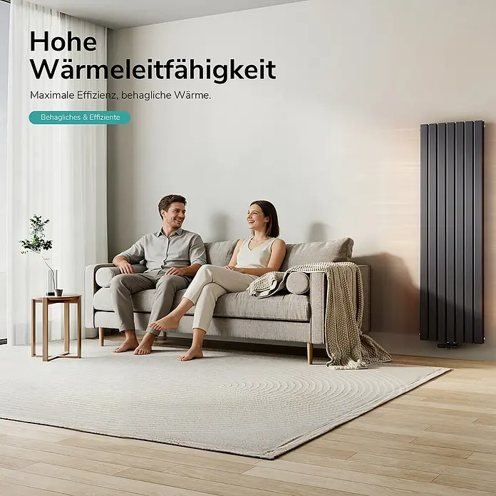 Emke Designheizkörper Flatrad FR - Wärmeleistung bei Vorlauftemperatur von 75 °C (D: 50): 1.949 W, Anthrazit - Hoher, dunkelgrauer Vertikalheizkörper in einem modernen Wohnzimmer, der einem auf dem Sofa entspannenden Paar Wärme spendet.
