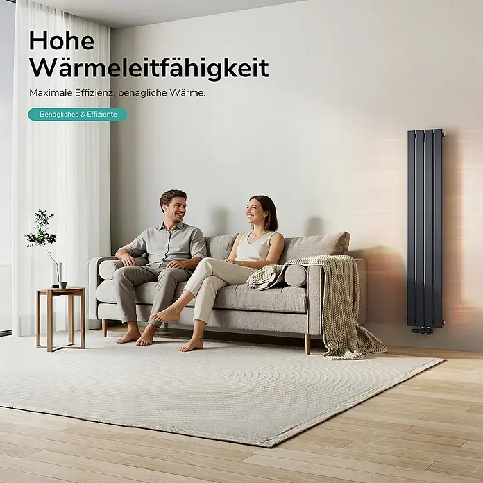 Emke Designheizkörper Flatrad FR - Wärmeleistung bei Vorlauftemperatur von 75 °C (D: 50): 557 W, Anthrazit - Hoher grauer Heizkörper an der Wand eines Wohnzimmers, der einem Paar auf dem Sofa Wärme spendet.