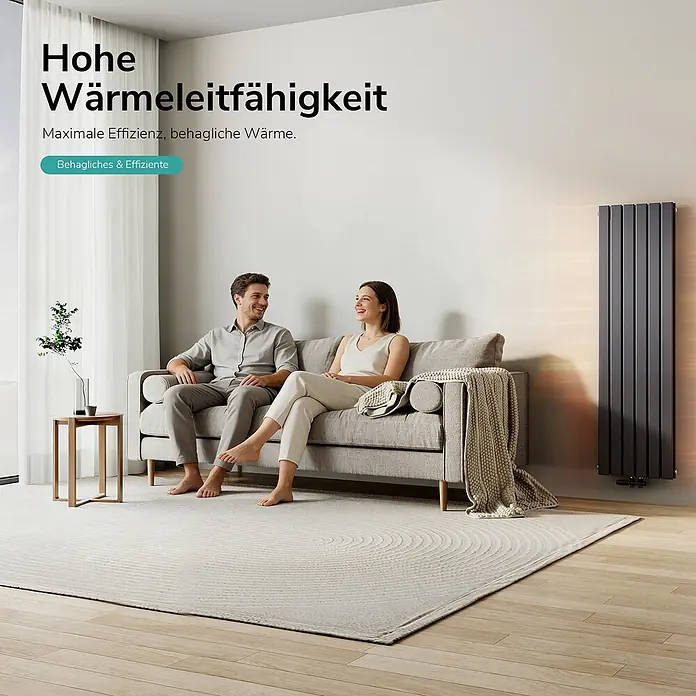 Emke Designheizkörper Flatrad FR - Wärmeleistung bei Vorlauftemperatur von 75 °C (D: 50): 1.490 W, Anthrazit - Hoher, dunkelgrauer Vertikalheizkörper heizt ein gemütliches Wohnzimmer, in dem ein Paar entspannt.