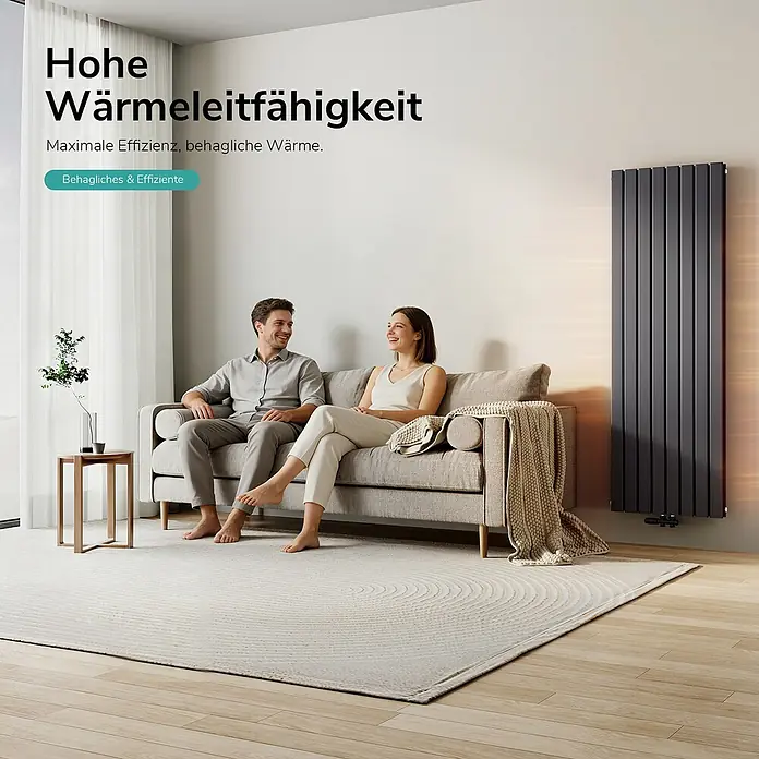 Emke Designheizkörper Flatrad FR - B x H: 62 x 180 cm, Wärmeleistung bei Vorlauftemperatur von 75 °C (D: 50): 2.227 W, Anthrazit - Hoher, dunkelgrauer Vertikalheizkörper wärmt ein modernes Wohnzimmer. Ein Paar sitzt bequem auf einem Sofa.