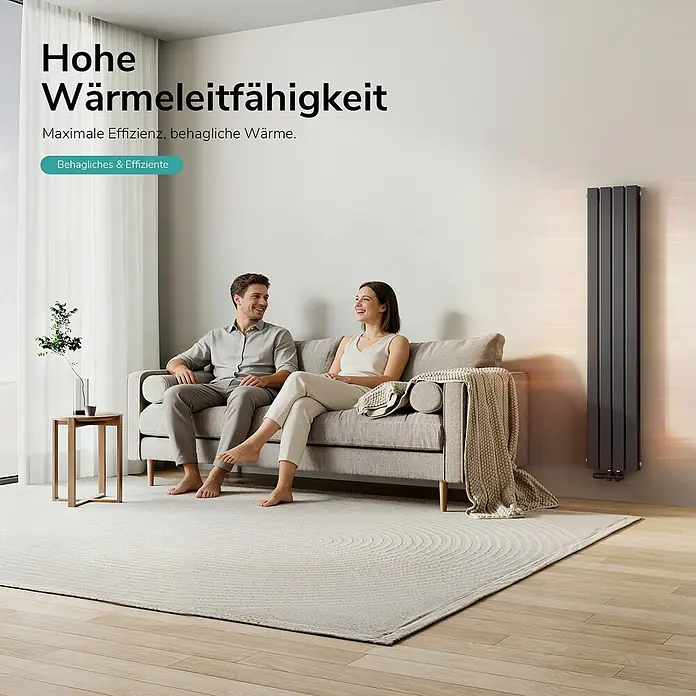 Emke Designheizkörper Flatrad FR - Wärmeleistung bei Vorlauftemperatur von 75 °C (D: 50): 889 W, Schwarz - Hoher, dunkelgrauer vertikaler Heizkörper in einem modernen Wohnzimmer, spendet einem Paar auf dem Sofa effiziente Wärme.