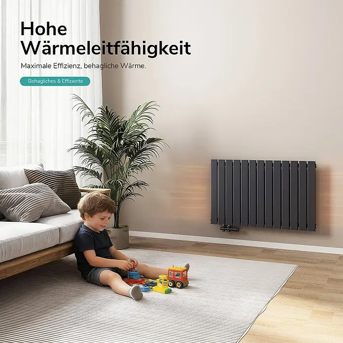 Emke Designheizkörper Flatrad FR - Wärmeleistung bei Vorlauftemperatur von 75 °C (D: 50): 730 W, Anthrazit - Dunkelgrauer Flachheizkörper an der Wand, der Wärme in einem Wohnzimmer abgibt, in dem ein Kind spielt.