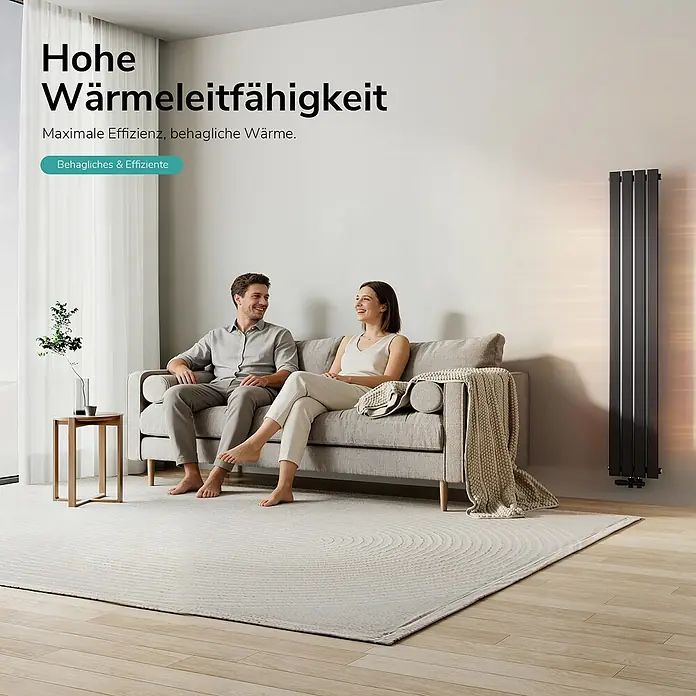 Emke Designheizkörper Flatrad FR - Wärmeleistung bei Vorlauftemperatur von 75 °C (D: 50): 627 W, Schwarz - Hoher, dunkelgrauer Vertikalheizkörper wärmt ein modernes Wohnzimmer, in dem ein Paar auf einem Sofa entspannt.