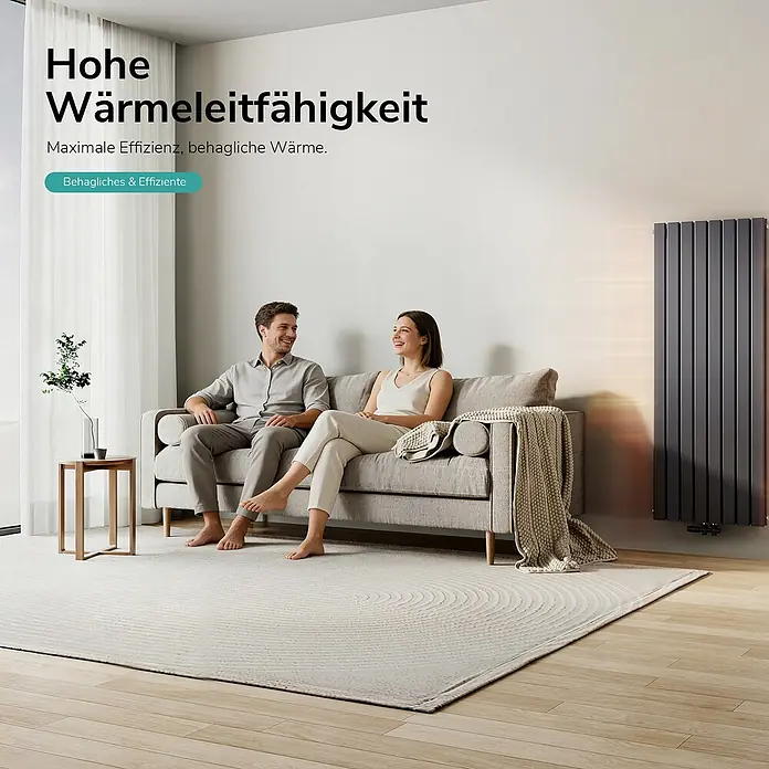 Emke Designheizkörper Flatrad FR - Wärmeleistung bei Vorlauftemperatur von 75 °C (D: 50): 1.988 W, Anthrazit - Ein schlanker, dunkelgrauer Vertikalheizkörper wärmt ein modernes Wohnzimmer, in dem ein Paar auf einem Sofa entspannt.
