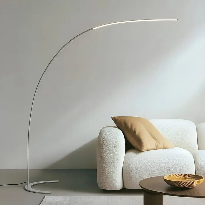 Lindby Stehleuchte Danua - alu / grau / zink, alu / grau / zink - Moderne silberne Bogenstehleuchte mit integriertem LED-Streifen, beleuchtet ein Wohnzimmersofa.