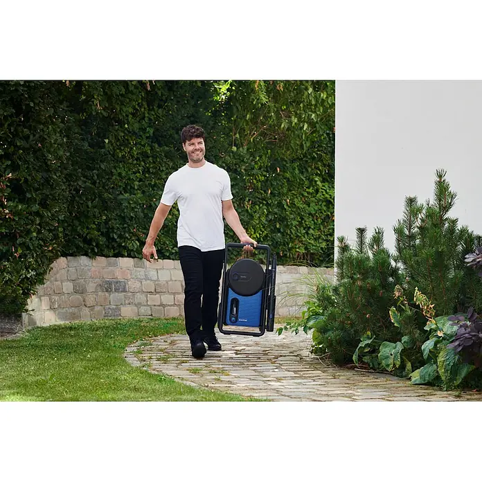 Nilfisk Hidrolimpiadora de alta presión Excellent 160-10 P EU - 160 bar, 2.100 W, Capacidad de bombeo: 450 l/h - Hombre lleva una hidrolavadora azul y negra en un jardín.